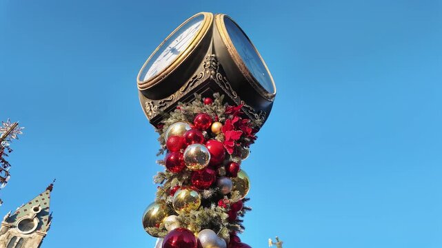 Ornate street clock tower is wrapped in red and gold christmas ornaments in batumi georgia.