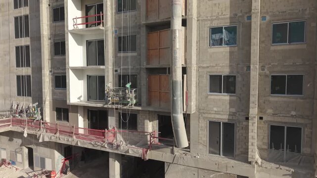 Building construction site with suspended scaffolding platform and chute
