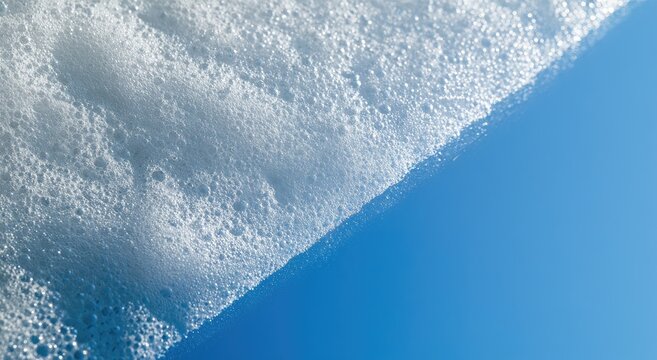 A close-up abstract view of white foam against a bright blue sky