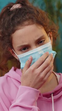 Sick preteen girl in medical protective face mask looking to camera. Young ill school child kid at home room apartment. Concept of quarantine, pandemic, pneumonia, allergy. Prevention virus diseases