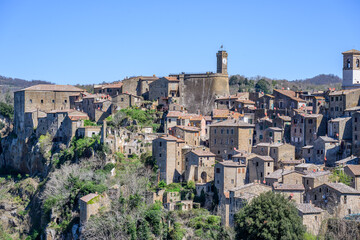 Fototapeta premium Old houses of Sorano stacked on a tufa ridge below the clock tower, Tuscany, Italy