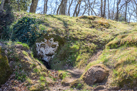 Carved stone faces in the tufa rock along the Via Cava di San Rocco, Sorano, Italy