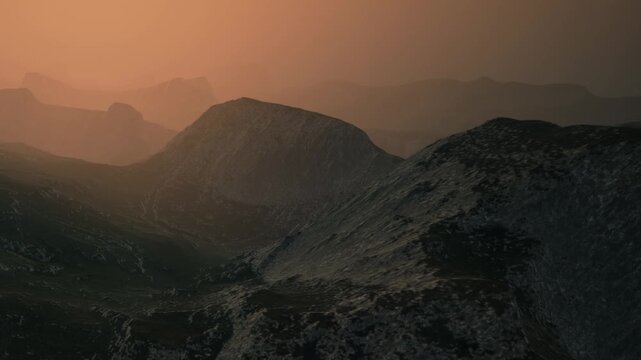 A vast mountain landscape is visible during sunset. The sun casts an orange hue across the terrain. Shadows and light define the shape of the mountains. A sense of openness is clear.