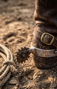 Rustic Cowboy Boot with Engraved Spur and Rope on Dusty Ground