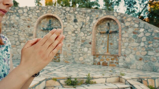 An Italian woman praying hands for peace in front of outdoor crucifix copy space
