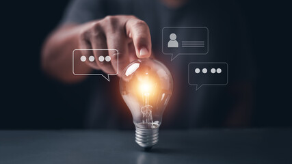 Innovation concept. Businessman touching glowing light bulb with chat bubbles and profile icon. Representing creative ideas, communication, customer feedback, brainstorming and business solution. © krungchingpixs