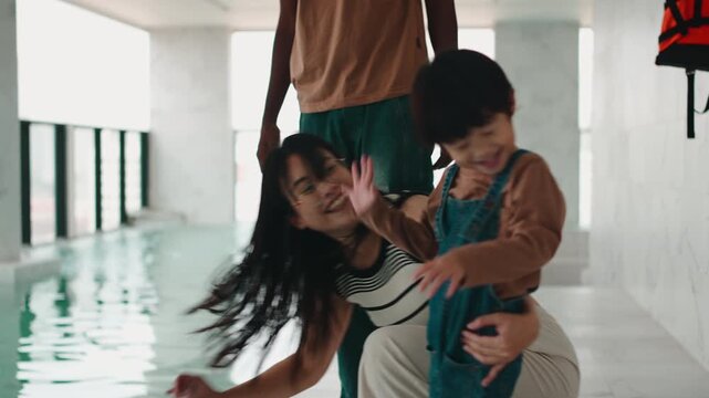 Playful family with a toddler son sharing time by an indoor pool