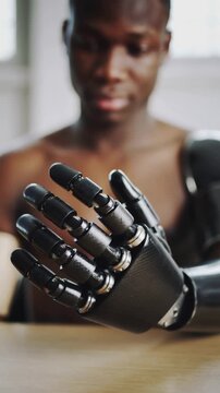 Black man looking at black bionic hand prosthesis in an interior setting, close up shot