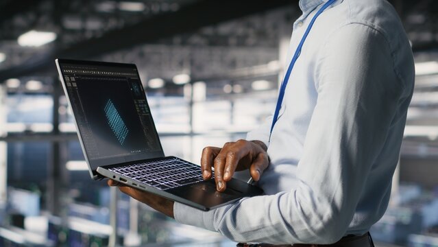 Server hub coworkers use a laptop to visualize large language model architecture and collaborate on neural network software tasks from an industrial platform.