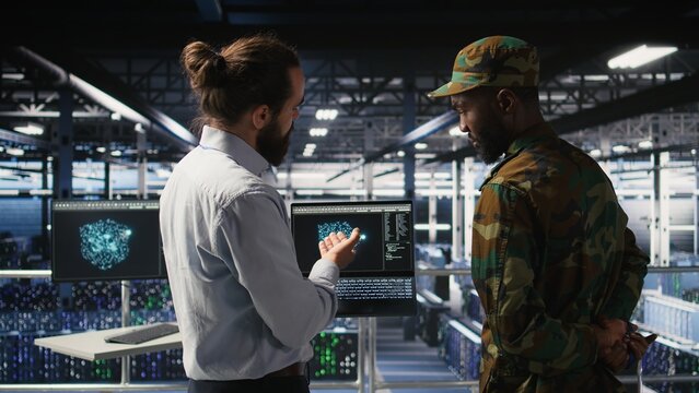 Military personnel oversee AI computing on laptops in a secure server facility; technical experts use artificial intelligence to monitor communications.