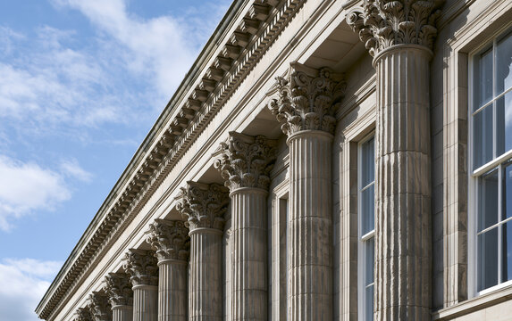 Grand Neoclassical Architecture with Iconic Columns and Reflective Windows Under a Bright Sky