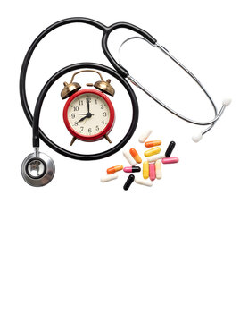 Close-up conceptual composition of a stethoscope, vintage alarm clock, and colorful capsule pills arranged artistically on a white background symbolizing health and timely medical care.