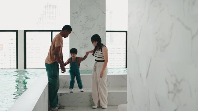 Mixed race family walking by an indoor pool in a modern building