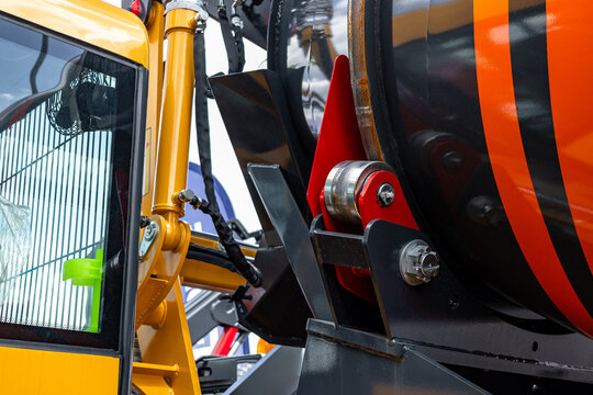 Concrete mixer truck drum support roller mechanism view. Modern construction machinery cement mixer chassis component with yellow cab and heavy duty industrial transport vehicle details.