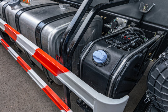 Semi truck adblue def tank with blue cap on chassis frame. Commercial heavy duty transport vehicle diesel exhaust fluid plastic reservoir with aluminum fuel tank engineering technical details.