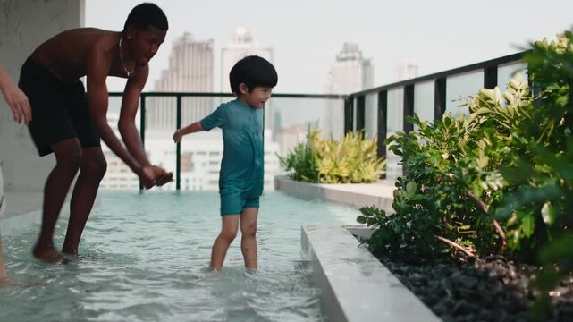 Happy little boy and father splashing water in a rooftop pool