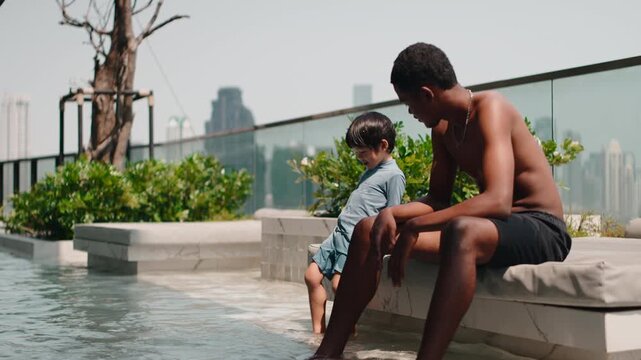 Black father and son enjoying a summer day at a rooftop pool