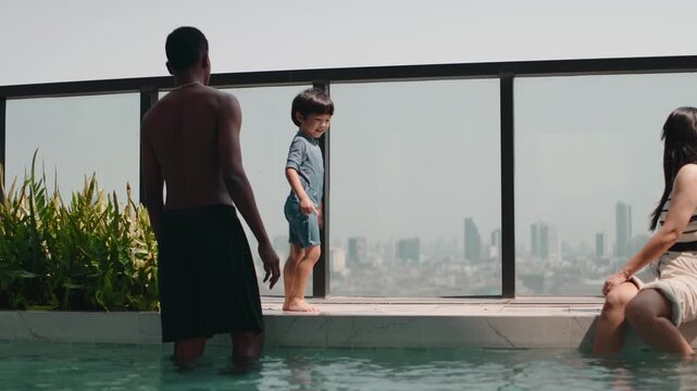 Young family with a son enjoying a rooftop pool with a skyline view