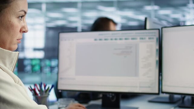 Smiling woman checks server bottlenecks at a PC from an alternate angle, connecting firewall issues, sluggish data transfer and technical troubleshooting.