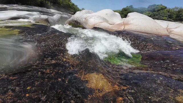 Clear river water flowing over smooth white rocks
