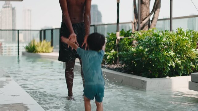 Joyful father and son splashing in a rooftop pool on a sunny day