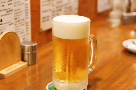 居酒屋のカウンター席に置かれたキンキンに冷えた生ビール