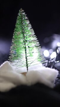 Una toma de cerca de un &aacute;rbol de navidad con hojas verdes con un fondo de luces de navidad. Video Vertical 