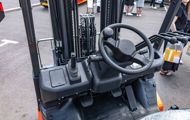 Industrial forklift steering wheel and hydraulic control levers. Modern warehouse warehouse material handling equipment cabin section with dashboard and logistics transport vehicle details. © NastyaPhoto