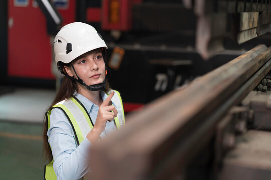 Woman engineer at work inspecting quality of industrial machinery used in manufacturing site