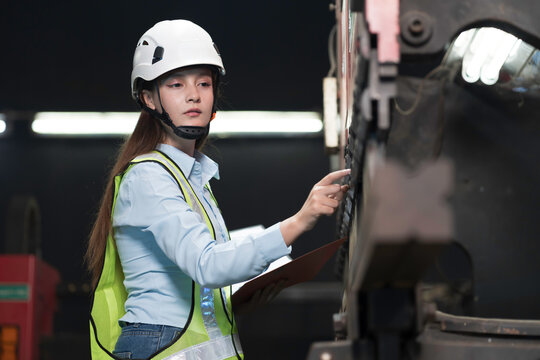 Woman engineer at work inspecting quality of industrial machinery used in manufacturing site