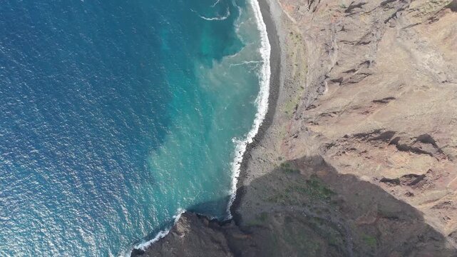 Aerial top down drone shot pushing in on the rugged, rocky coastline on Tenerife, Canary Islands. Features the beautiful turquoise waters of the Atlantic Ocean and Playa de Barranco Seco.
