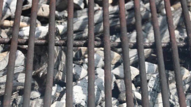 Glowing hot charcoal in barbecue grill pit with open flames close up background texture for bbq cooking and outdoor fire concept