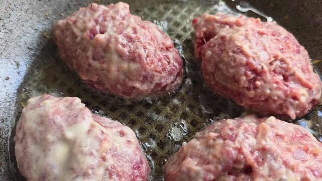 Raw minced meat cutlets cooking in a frying pan with hot bubbling oil for a homemade meal, showcasing the sizzling cooking process and preparation of a protein rich dish