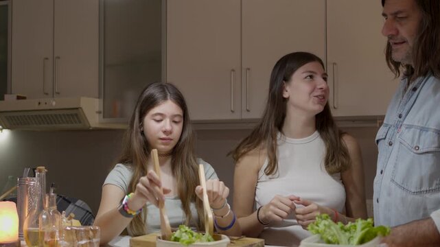 A cheerful family is having a good time in their kitchen while they prepare something together. They are all showing each other affection and they are happy.National cooking day