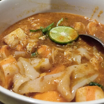 Delicious Indonesian spicy seblak soup with lime slice served in a white bowl
