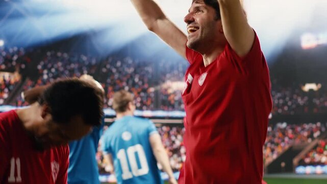 Happy diverse football players celebrating winning goal on pitch, with arms raised and clenched fists, devastated opponents while rivals hugging teammates and celebrating with cheering fans.
