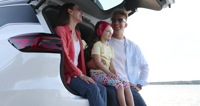 Happy family in trunk of car near sea