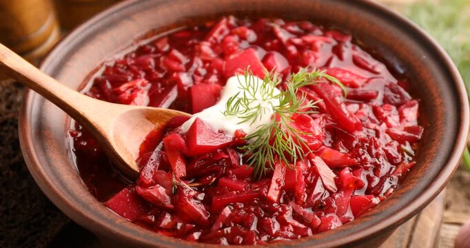 Eating tasty borscht with sour cream at table, closeup