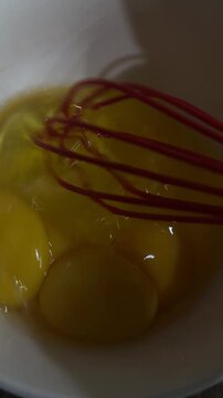 Whisking raw eggs in bowl close up cooking preparation