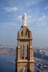 Fototapeta premium White Virgin Mary Statue Atop Santa Cruz Bell Tower with Oran Harbor Panorama