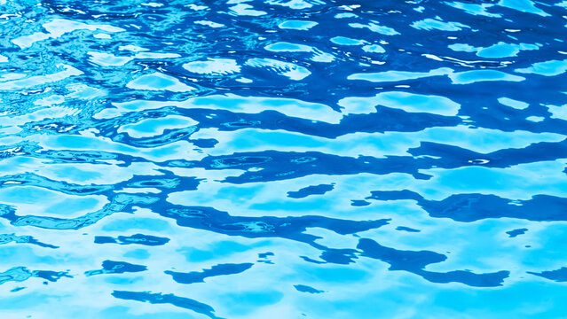 Blue water blurred surface with sunlight reflection and swimming pool ripples. Real photo non Ai generative
