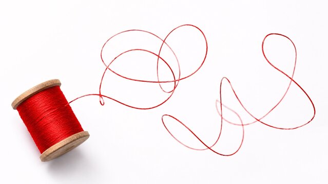 Tangled messy red sewing thread lying on a pure white background