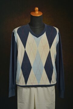 Argyle sweater with white trousers displayed on a mannequin 