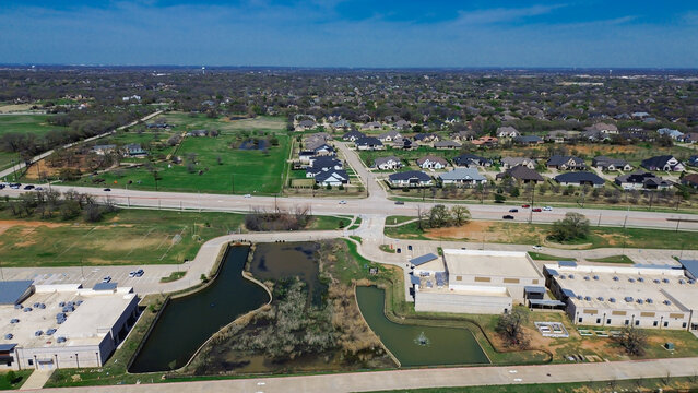Large retention pond borders custom luxury properties within Dallas suburb Flower Mound Road estates. Elevated view frames cul de sacs, private yards, swimming pools. Flower Mound, TX