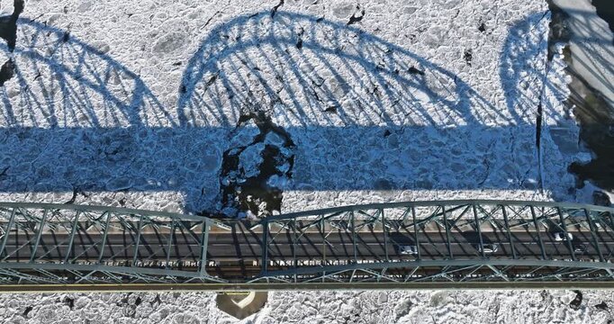 Bridge with traffic over a frozen river with ice floes.