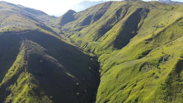 Ravine carved into the steep green mountainside creates a dramatic natural formation.