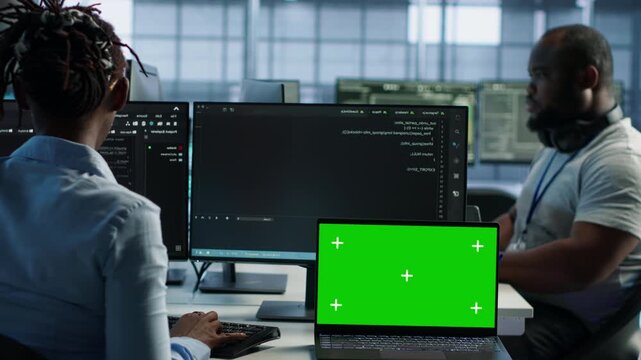 Team members developers in server hub using green screen laptop while capturing firewall review, server bottlenecks and technical problem solving.