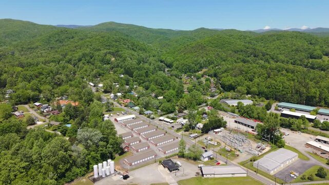 Aerial footage captures Brevard, North Carolina, highlighting green mountains, homes, and commercial structures in a scenic environment