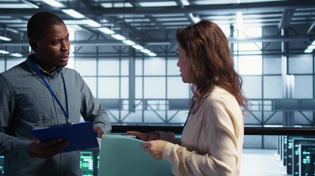 Server room staff handle system diagnostics with documents, combining compliance review, documentation review and technical coordination within a controlled technical environment.