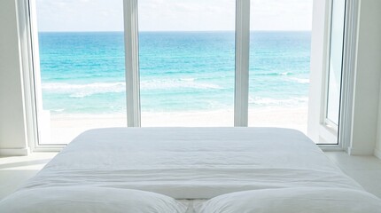 Fototapeta premium White bed facing large windows with a stunning turquoise ocean view
